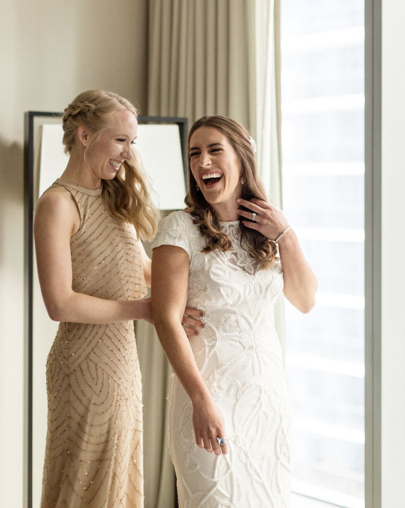 A unique Vizcaya Museum Wedding in Miami The Creatives Loft Weddings Miami bride and Maid of Honor laughing while dressing