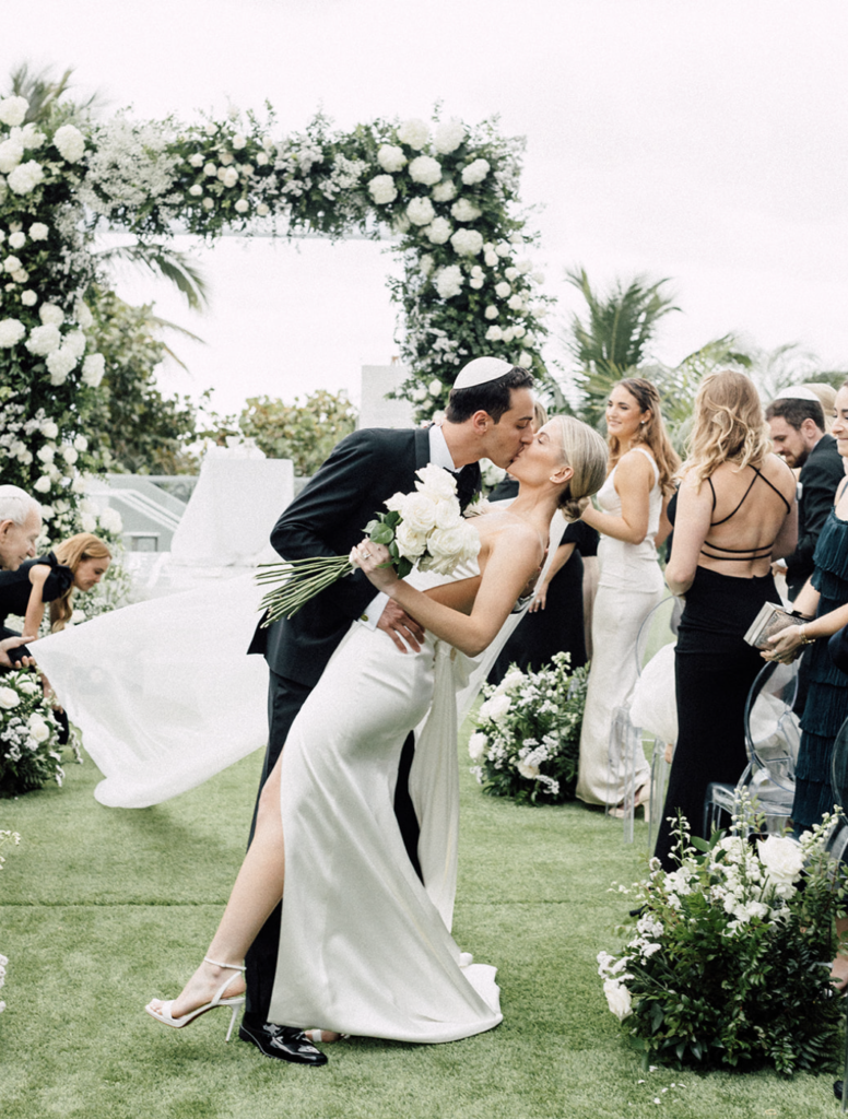 The newlyweds kissing at the ceremony aisle